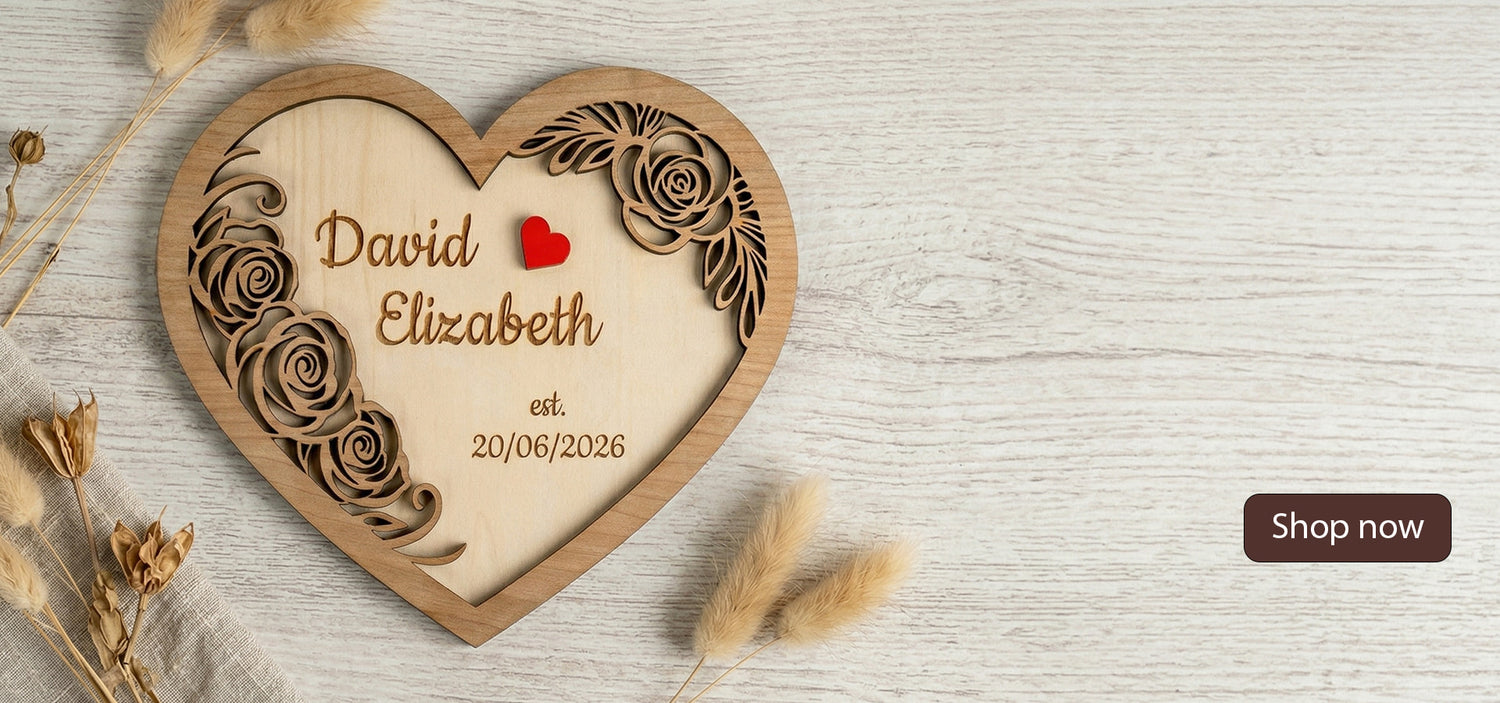 Wooden heart-shaped plaque with engraved names and date on a light wooden surface.