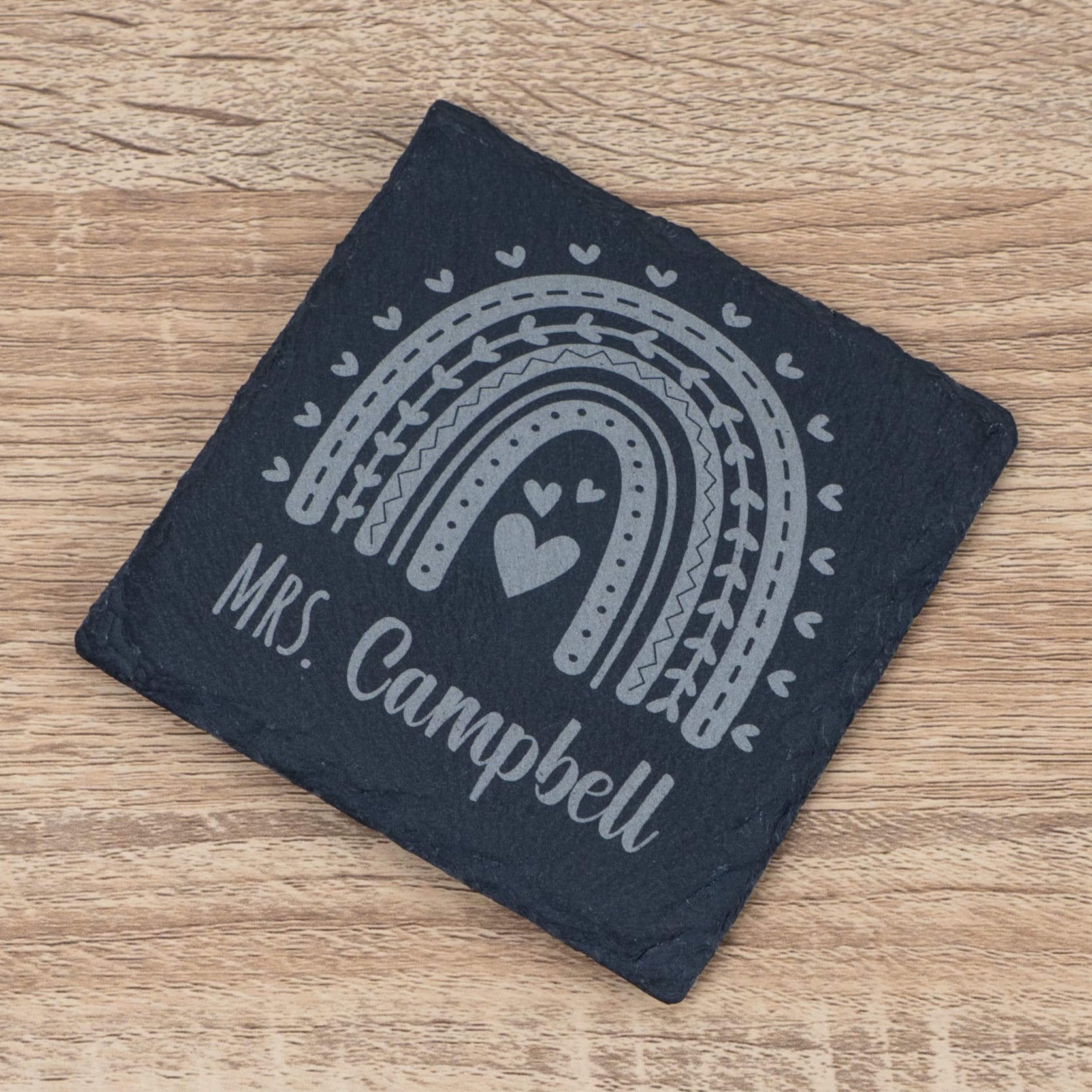 Personalised teacher slate coaster with rainbow design and 'Mrs. Campbell' engraving, a unique teacher gift.
