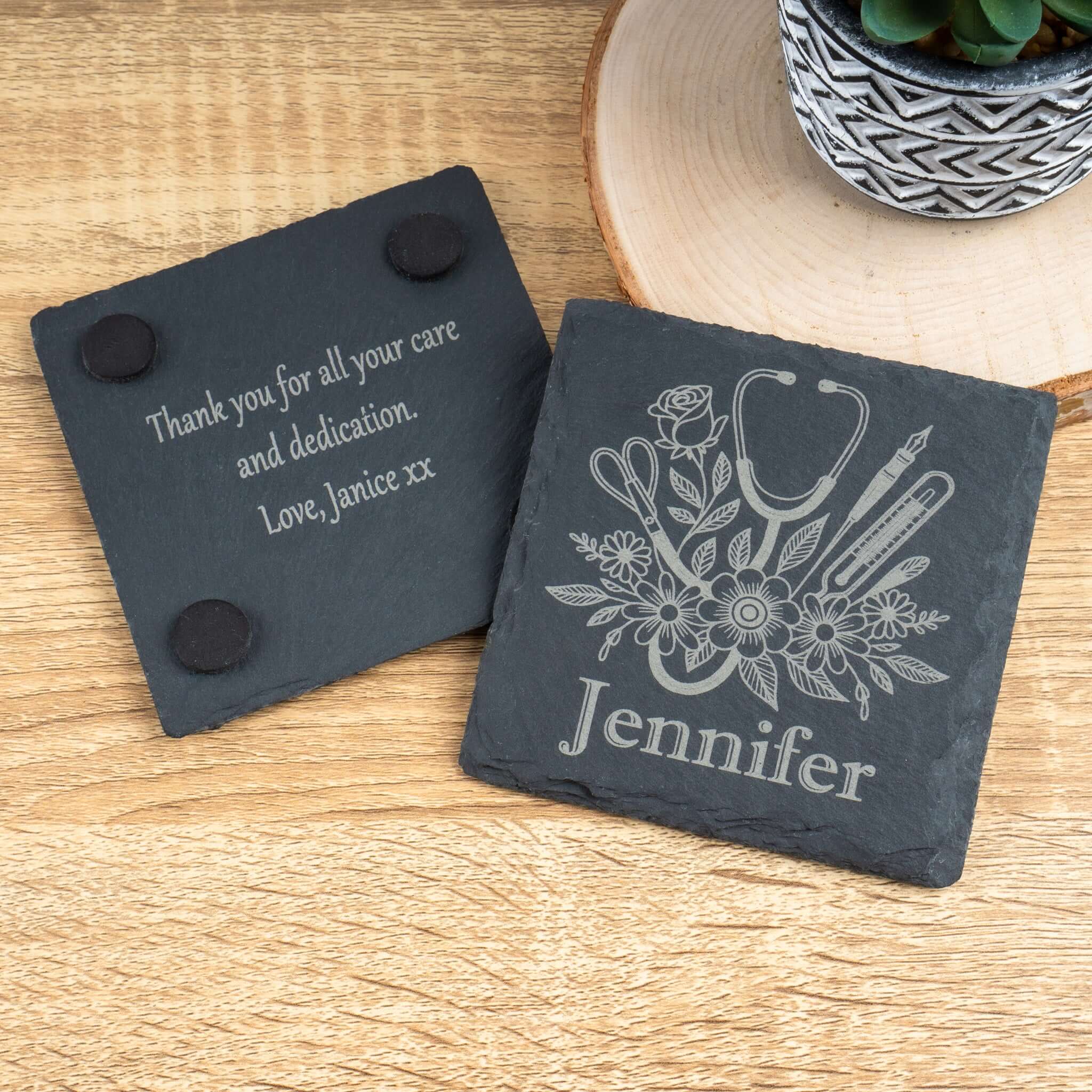 Two slate coasters with engraved designs on a wooden surface.