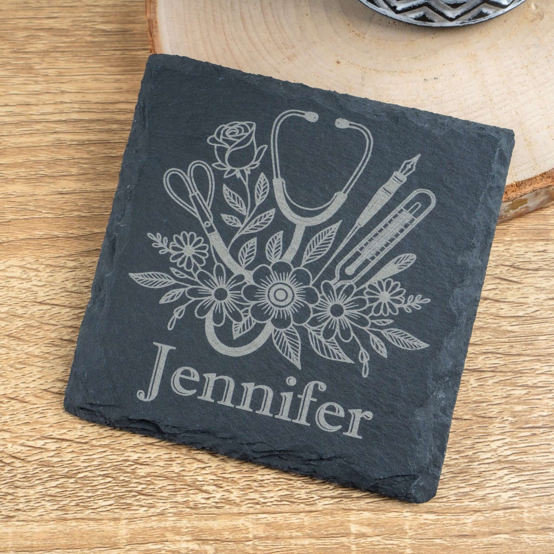 Slate coaster with medical-themed design and 'Jennifer' engraving on a wooden surface