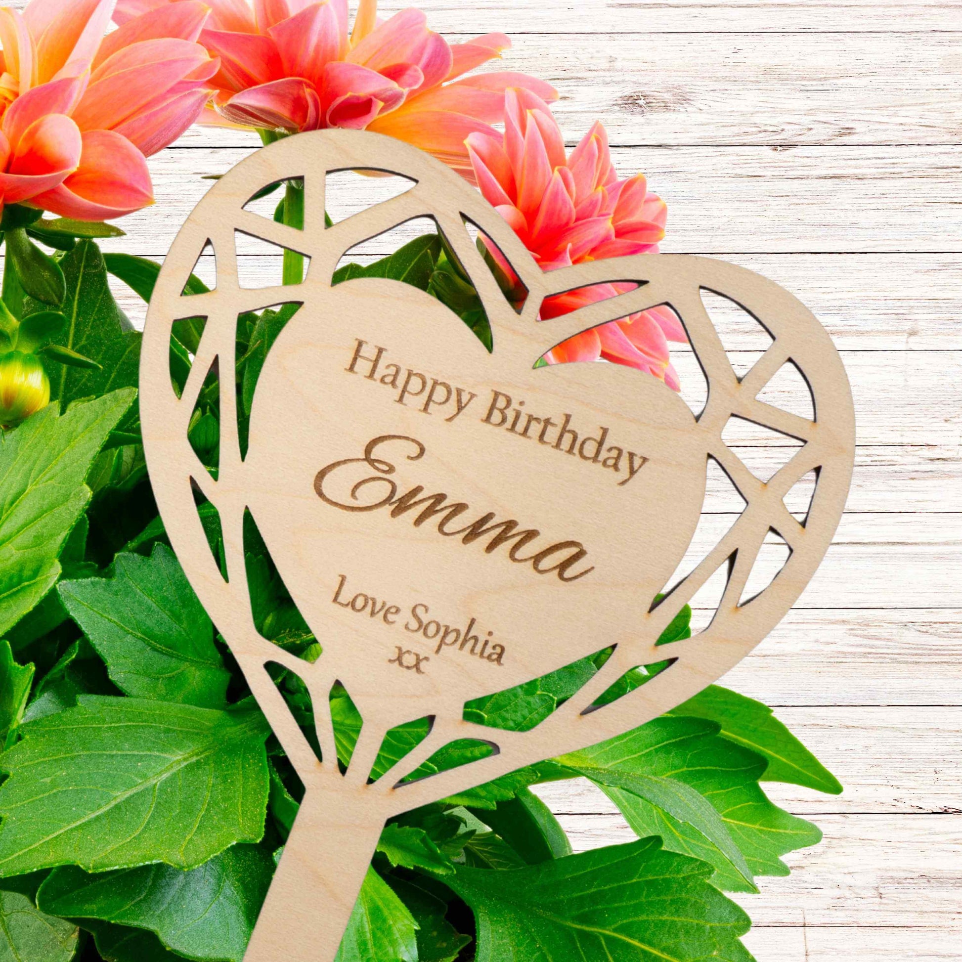 Personalised heart-shaped flower pot sign with the text 'Happy Birthday Emma Love Sophia' surrounded by vibrant flowers.