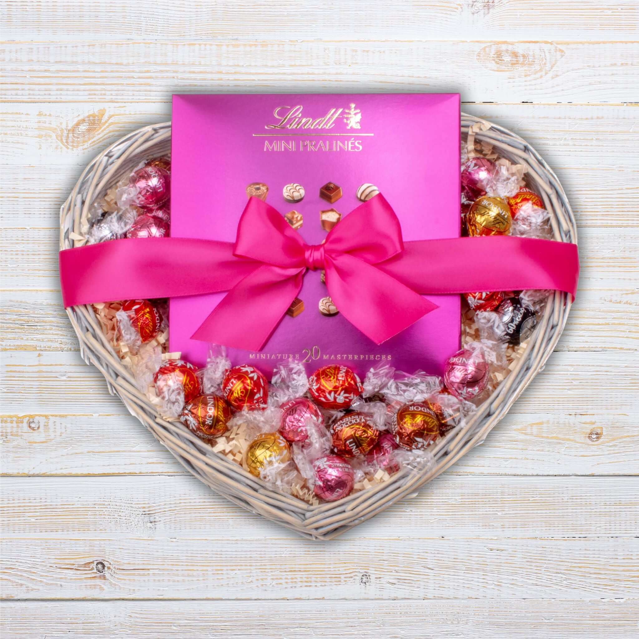 Lindt Indulgence Hamper featuring mini pralines wrapped in vibrant foil, elegantly presented in a heart-shaped wicker tray.