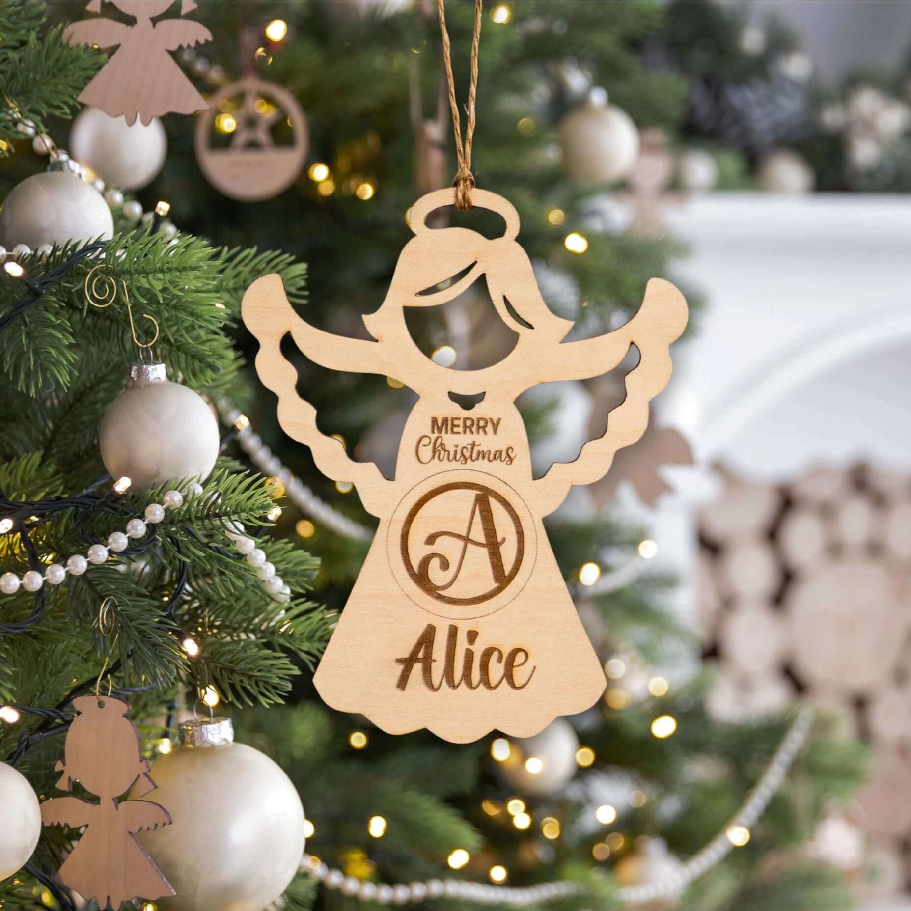 Wooden angel ornament with 'Merry Christmas Alice' text on a decorated Christmas tree.