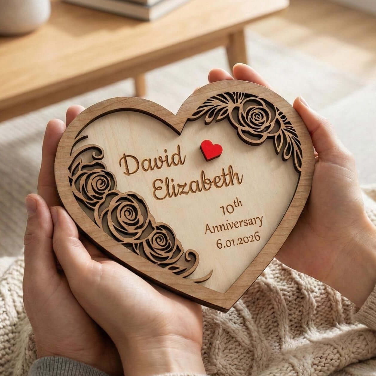 Personalised wooden heart keepsake for wedding anniversary, engraved with names and date, held in hands.