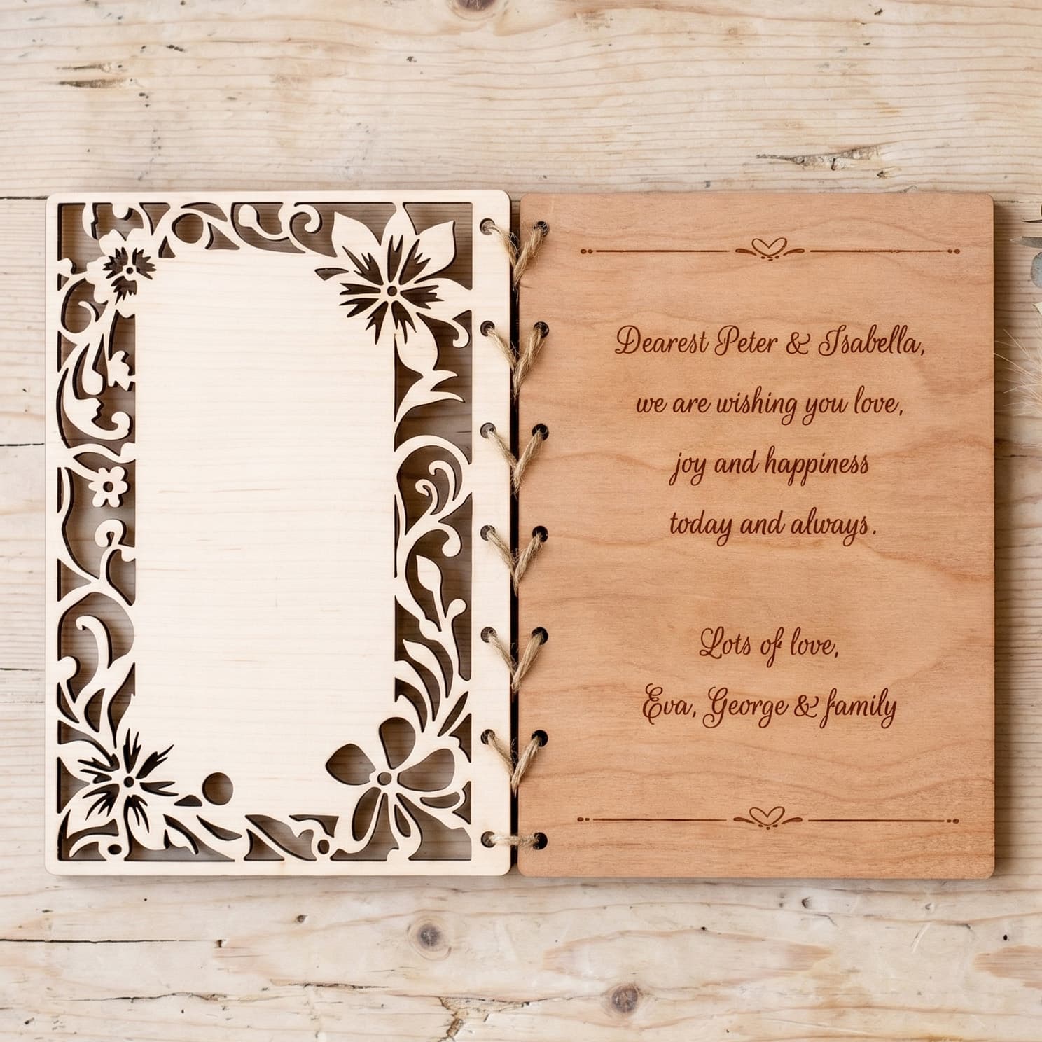 Wooden wedding card with floral design and engraved text on a wooden surface